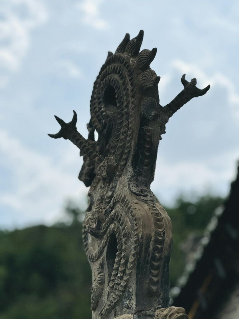 An intricately carved dragon sculpture set against a vibrant sky backdrop.