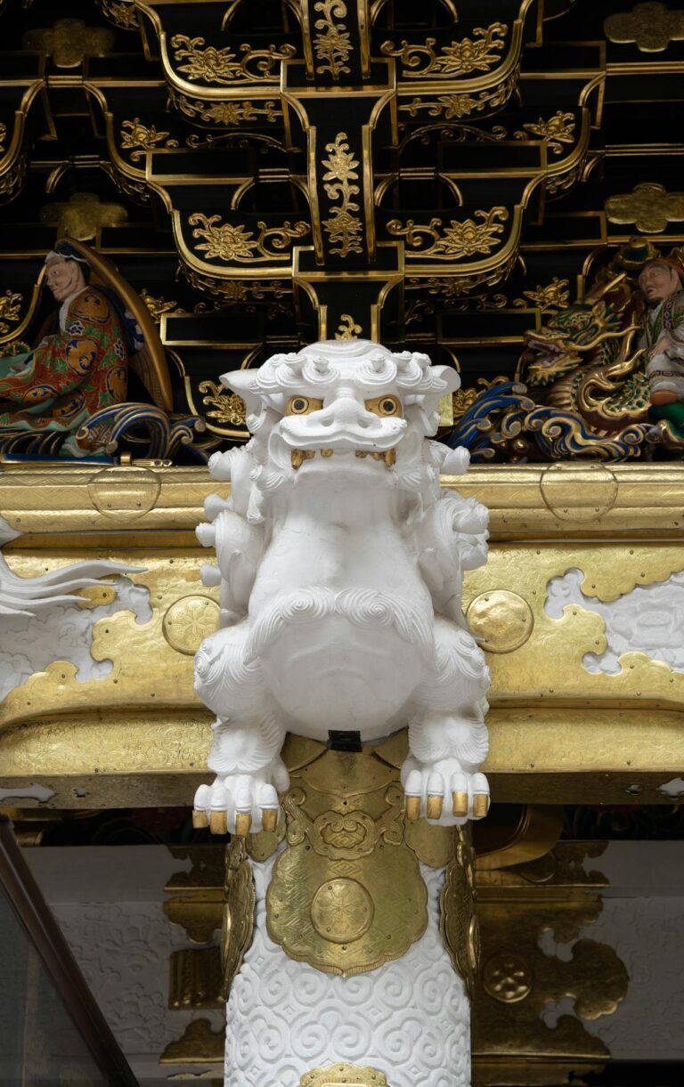Intricately carved temple guardian lion statue with ornate gold accents, showcasing traditional craftsmanship.
